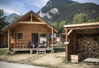 Montana Chalet træhytte i bjergene med to personer, der slapper af på verandaen om sommeren.