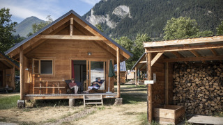 Montana Chalet Holzhütte in den Bergen mit zwei Personen, die sich auf der Veranda entspannen.