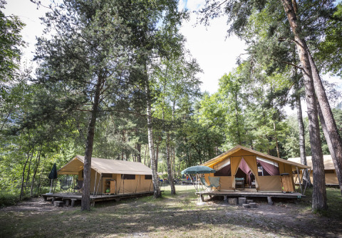 Tiendas glamping rodeadas de árboles en Huttopia Bourg Saint-Maurice, parque vacacional en Auvergne-Rhône-Alpes, Francia.