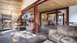 Sala luminosa con sofás, estantería y huéspedes en Huttopia Bourg Saint-Maurice, parque vacacional en Francia.
