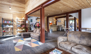 Sala luminosa con sofás, estantería y huéspedes en Huttopia Bourg Saint-Maurice, parque vacacional en Francia.