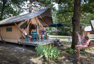Gezin relaxt buiten hun tent in Huttopia Bourg Saint-Maurice, vakantiepark in Auvergne-Rhône-Alpes, Frankrijk.