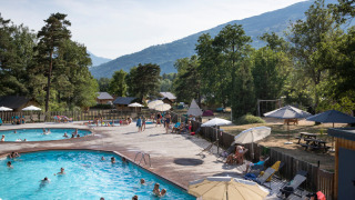 Piscina al aire libre en Huttopia Bourg Saint-Maurice con familias disfrutando de la naturaleza y las montañas.