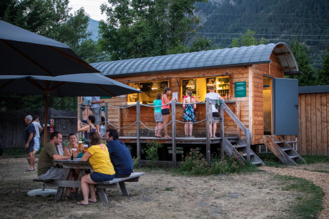 Huéspedes disfrutan en una barra de madera y mesa de picnic en Huttopia Bourg Saint-Maurice, Francia.