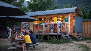 Huéspedes disfrutan en una barra de madera y mesa de picnic en Huttopia Bourg Saint-Maurice, Francia.