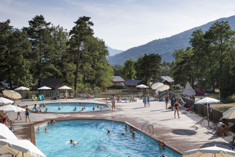 Personas disfrutando de las piscinas en Huttopia Bourg Saint-Maurice, parque vacacional en Auvergne-Rhône-Alpes, Francia.