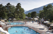 People swimming and relaxing by the pools at Huttopia Bourg Saint-Maurice holiday park in Auvergne-Rhône-Alpes, France.