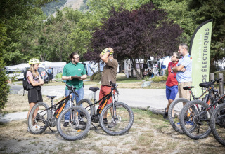Mensen verzamelen zich bij elektrische fietsen in vakantiedomein Huttopia Bourg Saint-Maurice, Frankrijk.