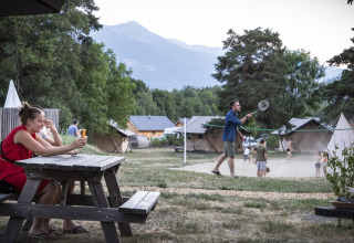 Vakantiepark Huttopia Bourg Saint-Maurice in Frankrijk, mensen ontspannen en spelen badminton buiten.