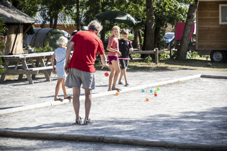 Gezin speelt jeu de boules op een zonnige dag bij Huttopia Bourg Saint-Maurice vakantiepark in Auvergne-Rhône-Alpes.