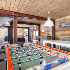 Sala de juegos con futbolín, paredes de madera y muebles modernos en Huttopia Bourg Saint-Maurice.