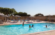 Udendørs swimmingpool ved Huttopia Meursault feriested med børn der leger og liggestole rundt omkring.