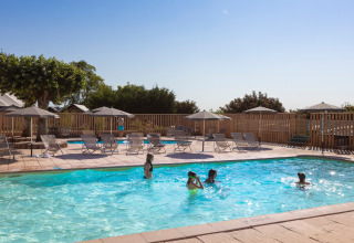 Outdoor swimming pool at Huttopia Meursault holiday park with children playing and sun loungers nearby.