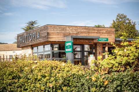 Entrance of Huttopia Meursault holiday park in Bourgogne-Franche-Comté, France, with a modern wood-clad building.