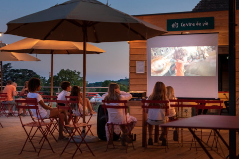 Niños ven una película al aire libre bajo sombrillas en Huttopia Meursault, un resort en Borgoña, Francia.