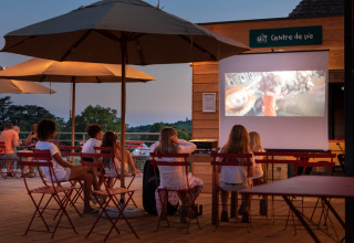 Kinderen kijken naar een openluchtfilm onder parasols bij Huttopia Meursault, Bourgogne, Frankrijk.