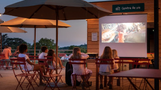 Niños ven una película al aire libre bajo sombrillas en Huttopia Meursault, un resort en Borgoña, Francia.