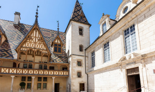 Edificio histórico con techo de azulejos coloridos en Meursault, Bourgogne-Franche-Comté, Francia bajo el sol.