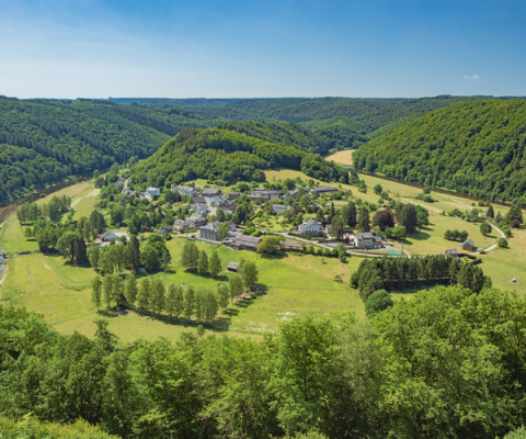 Vista aérea de Huttopia Vallée de la Semois, un parque vacacional en Namur, Bélgica, rodeado de verdes colinas.