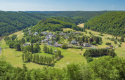 Vista aérea de Huttopia Vallée de la Semois, un parque vacacional en Namur, Bélgica, rodeado de verdes colinas.