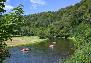 Kajakkers op een rustige rivier tussen groene heuvels in Huttopia Vallée de la Semois, Namur, België.