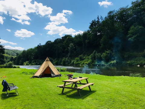 Zona de campamento con tienda, río y mesa de picnic en Huttopia Vallée de la Semois, Namur, Bélgica.