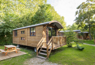 Casetta in legno su ruote con veranda e tavolo da picnic a Huttopia Vallée de la Semois, Namur, Belgio.