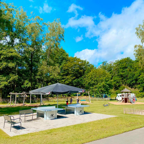 Parque infantil y mesas de ping-pong al aire libre rodeados de naturaleza verde en Vallée de la Semois, Bélgica.