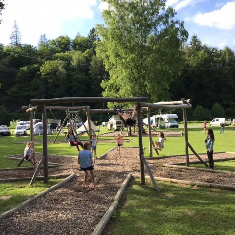 Niños jugando en columpios de madera en el parque vacacional Huttopia Vallée de la Semois en Namur, Bélgica.