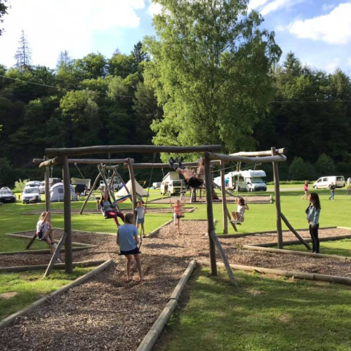 Kinder schaukeln auf einem Holzspielplatz im Ferienpark Huttopia Vallée de la Semois, Namur, Belgien.