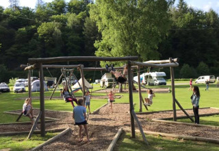 Children playing on a wooden swing set at Huttopia Vallée de la Semois holiday park in Namur, Belgium.