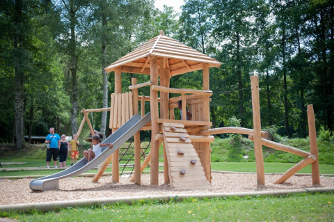 Niños juegan en un parque infantil de madera con tobogán en Huttopia Vallée de la Semois, Namur, Bélgica.