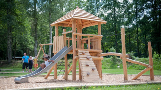 Niños juegan en un parque infantil de madera con tobogán en Huttopia Vallée de la Semois, Namur, Bélgica.