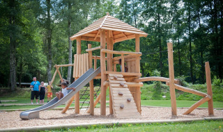 Niños juegan en un parque infantil de madera con tobogán en Huttopia Vallée de la Semois, Namur, Bélgica.