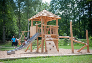 Des enfants jouent sur une aire de jeux en bois avec toboggan à Huttopia Vallée de la Semois, Namur, Belgique.