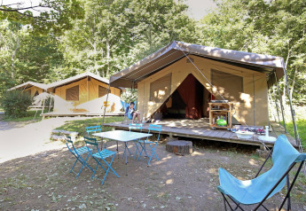 Safari tent Toile&Bois Sweet bij Huttopia Royat in Frankrijk met buitenstoelen, omgeven door groene bomen.
