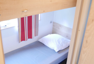 Litera de madera con cama individual en la cabaña Gypsy caravan de Huttopia Royat, Francia.