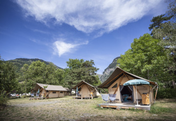 Safari telte Trappeur hos Huttopia Bourg Saint-Maurice, Frankrig, med bjerge og grønt i baggrunden.