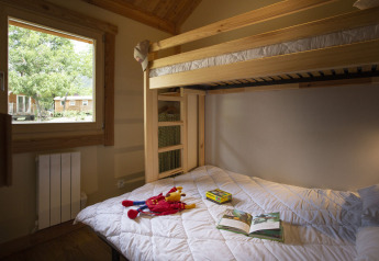 Udsigt over et hyggeligt værelse med køjesenge og vindue i Montana Chalet på Huttopia Bourg Saint-Maurice, Frankrig.