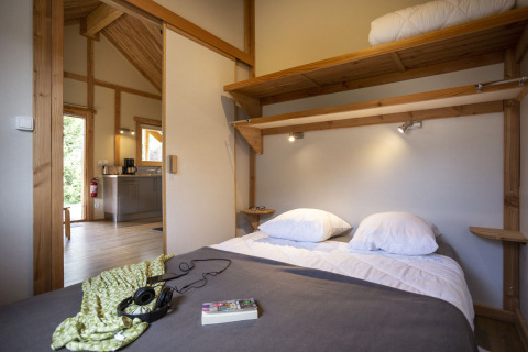 Soveværelse i Montana Chalet på Huttopia Bourg Saint-Maurice med dobbeltseng og træinteriør.