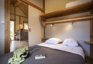 Soveværelse i Montana Chalet på Huttopia Bourg Saint-Maurice med dobbeltseng og træinteriør.
