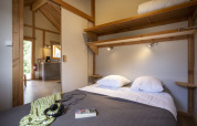Dormitorio del Montana Chalet en Huttopia Bourg Saint-Maurice, Francia, con cama doble y decoración de madera.