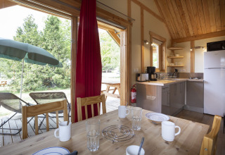 Hyggelig Montana Chalet-hytte på Huttopia Bourg Saint-Maurice med spisebord, tekøkken og udendørs terrasse.