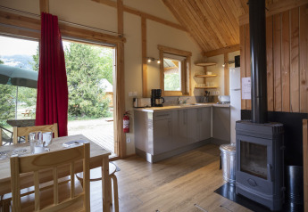 Interiør af Montana Chalet i Huttopia Bourg Saint-Maurice, Frankrig, med moderne køkken og brændeovn.