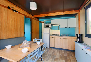 Modern kitchen and dining area in Chalet Evasion at Huttopia Meursault, France, with wood interior.