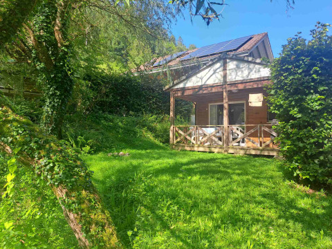 Knusse glampingaccommodatie in een vakantiepark, omgeven door natuur en gras onder een stralend blauwe lucht.