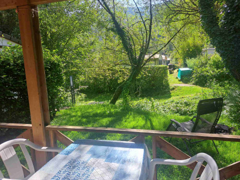 Udsigt fra en glampinghytte mod en grøn have med træer og campingvogne i en ferielejr.