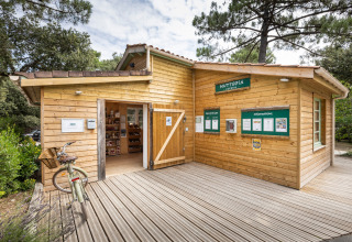 Onthaalgebouw van Huttopia Oléron Les Chênes Verts vakantiepark, midden tussen bomen in Nouvelle-Aquitaine, Frankrijk.