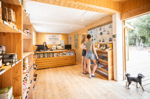 Reception area at Huttopia Oléron Les Chênes Verts in France, two women and a dog browsing information items.