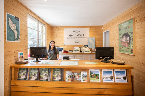 Recepcionista tras el mostrador en Huttopia Oléron Les Chênes Verts, parque vacacional en Nouvelle-Aquitaine, Francia.